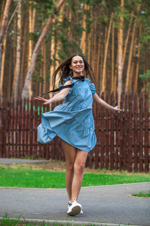 Young beautiful brunette woman in a turquoise summer dress, summer park outdoorsの写真素材