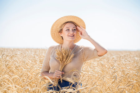 Portrait of a young beautiful blonde woman posing in a wheat fieldの写真素材