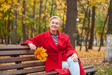 Autumn portrait of a middle aged woman in a red coatの写真素材