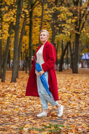 Autumn portrait of a middle aged woman in a red coatの写真素材
