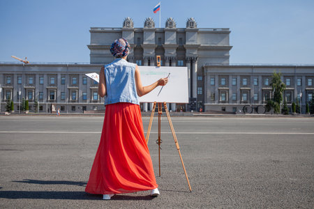 Female artist paints a cityscape in Samaraの写真素材