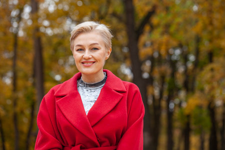 Autumn portrait of a middle aged woman in a red coatの写真素材