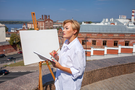Female artist paints a cityscape in Samaraの写真素材