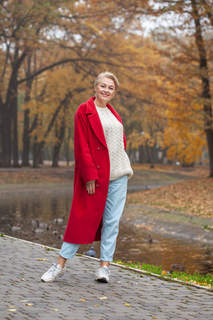 Full length portrait of a middle aged woman in an autumn parkの写真素材
