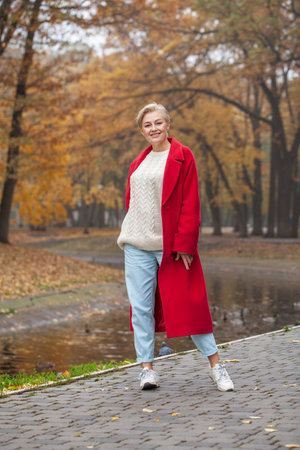 Full length portrait of a middle aged woman in an autumn parkの写真素材