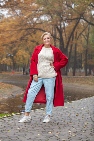 Full length portrait of a middle aged woman in an autumn parkの写真素材