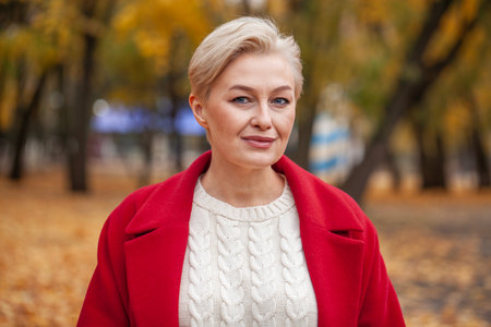 Autumn portrait of a middle aged woman in a red coatの写真素材