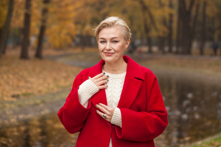 Portrait of a beautiful middle-aged woman in a red autumn coatの写真素材