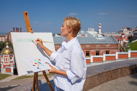 Female artist paints a cityscape in Samaraの写真素材