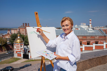 Female artist paints a cityscape in Samaraの写真素材