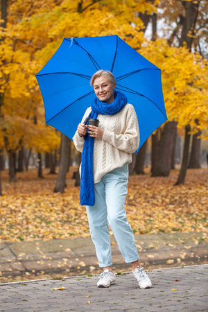 Full length portrait of a middle aged woman in an autumn parkの写真素材