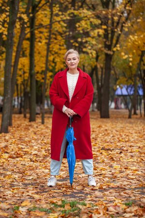 Autumn portrait of a middle aged woman in a red coatの写真素材