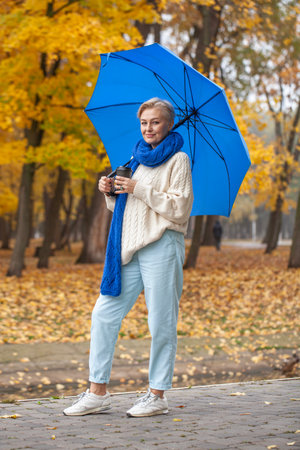 Full length portrait of a middle aged woman in an autumn parkの写真素材