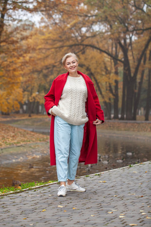 Full length portrait of a middle aged woman in an autumn parkの写真素材