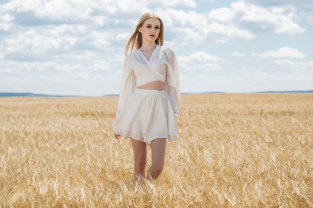 Portrait of a young beautiful blonde girl posing in a wheat fieldの写真素材