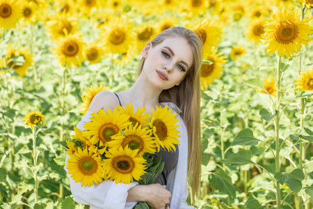 Young beautiful blonde girl with a bouquet of sunflowersの写真素材