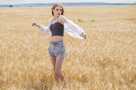 Portrait of a young beautiful blonde girl posing in a wheat fieldの写真素材