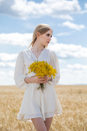 Portrait of a young beautiful blonde girl posing in a wheat fieldの写真素材