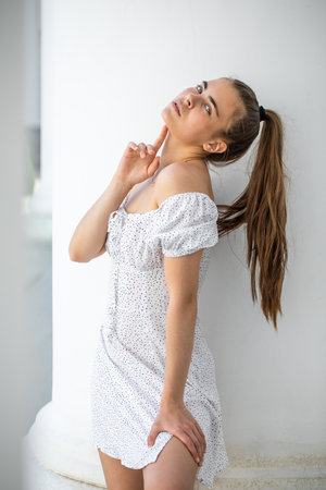 Portrait of a young beautiful brunette girl in a white summer dress with open shouldersの写真素材