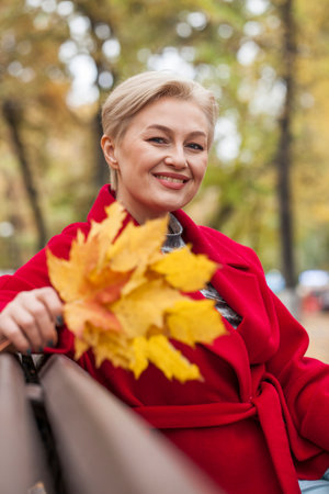 Portrait of a beautiful middle-aged woman in a red autumn coatの写真素材