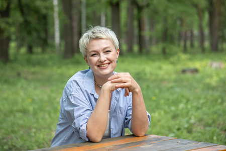 Portrait of a beautiful blonde middle-aged woman in a summer parkの写真素材