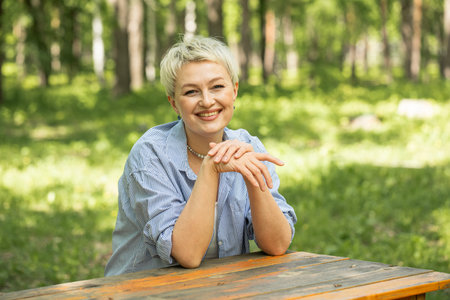 Portrait of a beautiful blonde middle-aged woman in a summer parkの写真素材