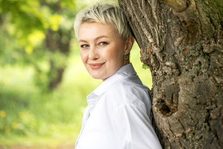 Portrait of a beautiful blonde middle-aged woman in a summer parkの写真素材