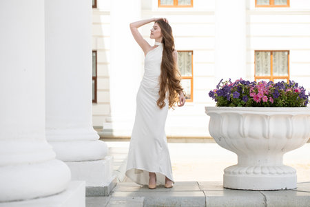 Full-length portrait of a young beautiful woman in a long white dressの写真素材