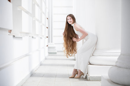 Full-length portrait of a young beautiful woman in a long white dressの写真素材