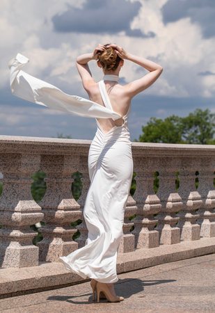 Full-length portrait of a young beautiful woman in a long white dressの写真素材