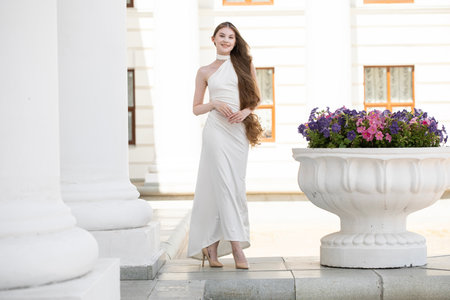 Full-length portrait of a young beautiful woman in a long white dressの写真素材