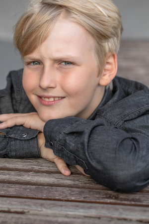 Portrait of a blond teenage boy in the yard on the streetの写真素材