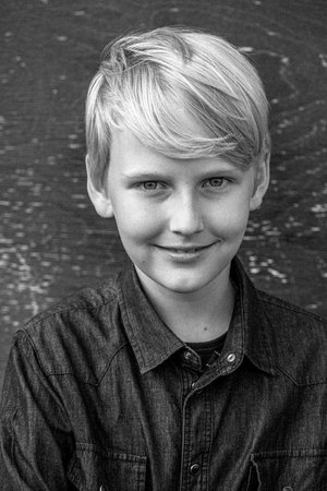 Portrait of a blond teenage boy in the yard on the street