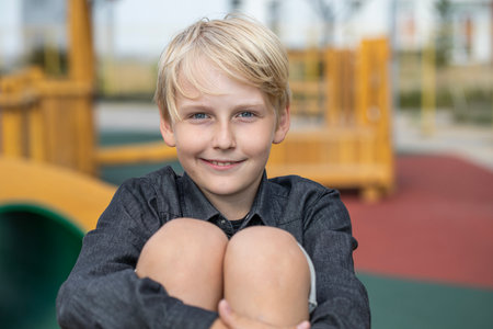 Portrait of a blond teenage boy in the yard on the street