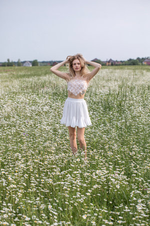 Young beautiful blonde girl posing in a chamomile fieldの写真素材