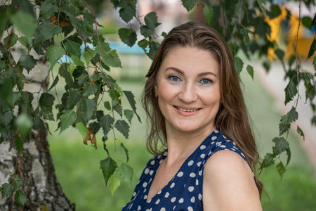 Close up portrait of a beautiful middle-aged woman in a summer park