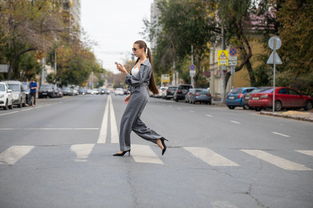 A young businesswoman walks along a pedestrian crossingの写真素材