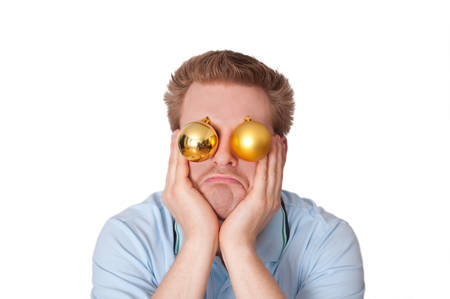 Funny image: Stressed, disappointed, frustrated young man with christmas baubles leaning his face on his hands in front of a white backgroundの写真素材