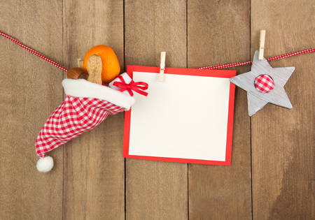 Red and white chequered santa hat with Christmas decoration and a white label in front of a wooden backgroundの写真素材