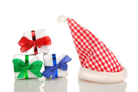 three white christmas packets with coloured bows and chequered santa hat in front of a white backgroundの写真素材