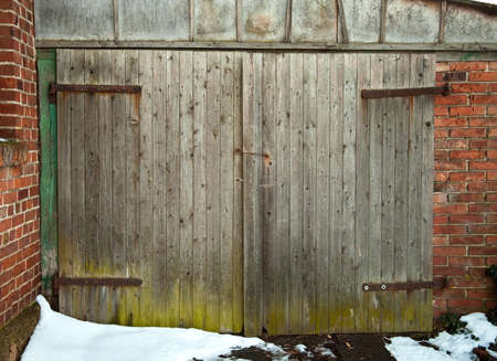 old wooden barn door with green base and snowの写真素材