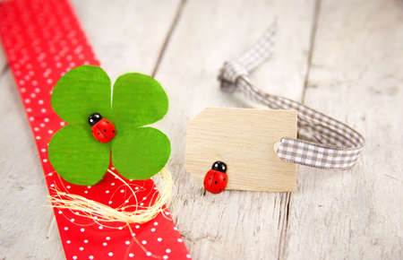 Shamrock and ladybugs as lucky symbols with empty message board on wooden backgroundの写真素材