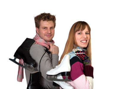 Young woman and man holding ice skates in front of white backdropの写真素材