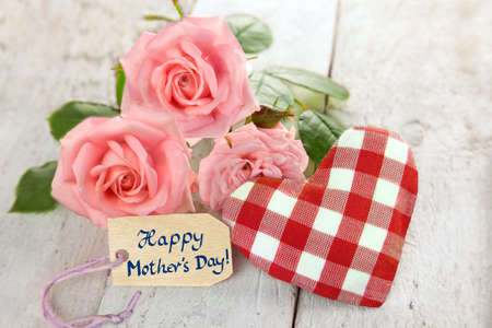 Handwritten text with roses red and white checkered fabric heart on wooden planksの写真素材