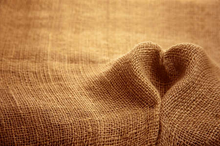 Rustic jute sackcloth fabric textile texture folded in heart shape backdrop

の写真素材