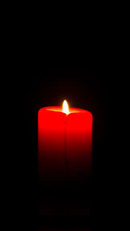 Red candle is burning on a black backgroundの写真素材