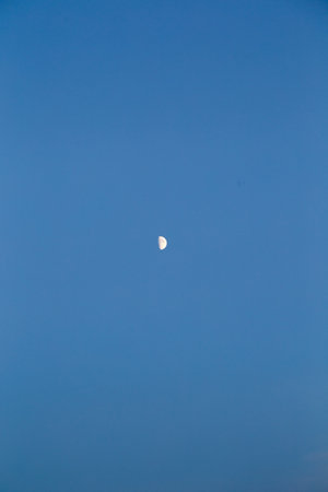 The moon on the background of a clear blue sky, bright lightの写真素材