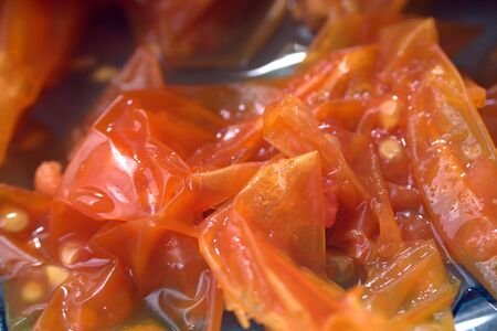 Tomato skins close up on blue glass plateの写真素材
