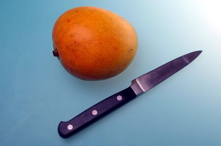 mango on blue cutting board with knifeの写真素材