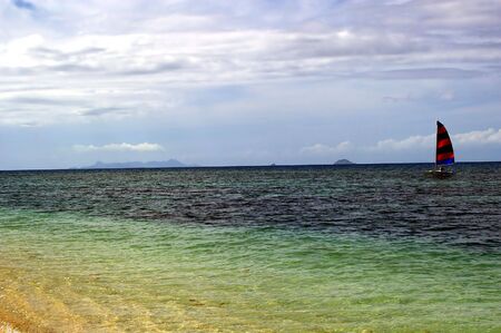 sailboat on the blue waters and sky of fijiの写真素材